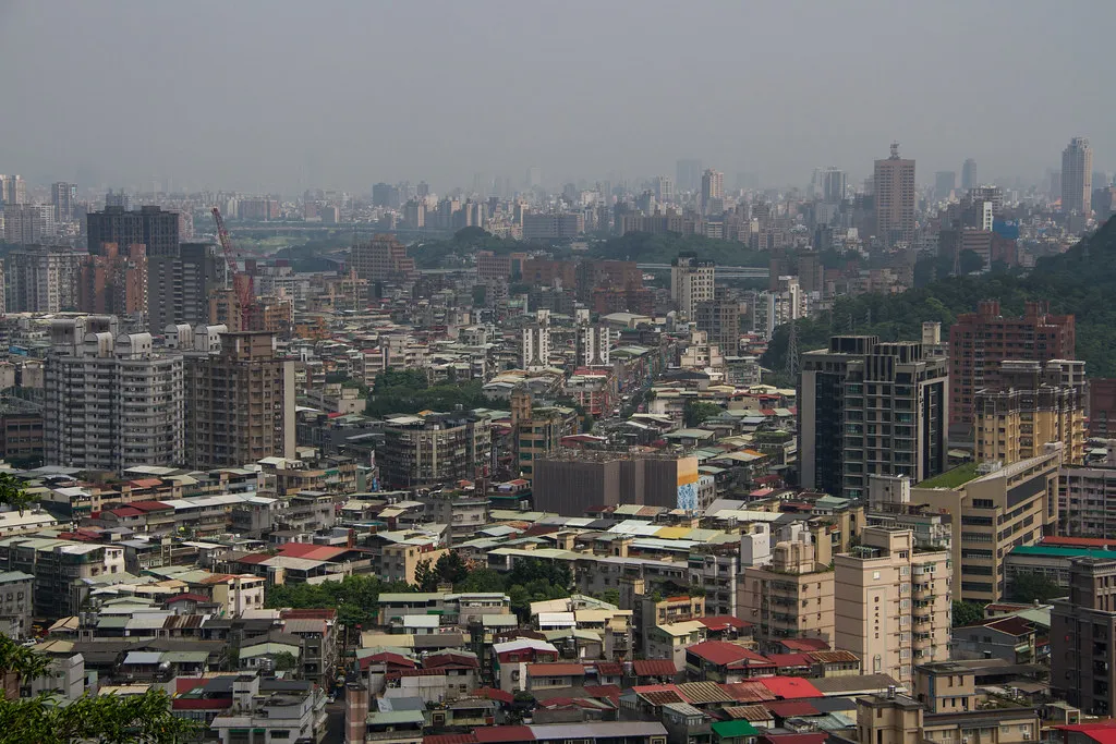 Dense rooftops and apartment towers of Taipei seen from a hillside
